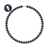 Le Collier NOELYSE de Perlinea, orné de perles de culture noires rondes de 9/10 mm et d'un fermoir mousqueton en argent, est présenté dans un cercle. Un badge bleu "Artisan Bijoutier Français" avec le drapeau français apparaît en haut à gauche sur fond blanc.