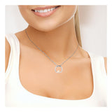 Une femme vêtue d'un haut blanc sourit, portant le collier Perlinea CIRCLE | Argent & Perle de Culture Rose - un délicat collier en argent 925 avec un pendentif circulaire orné d'une seule perle de culture rose.