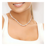 Une femme porte le Perlinea Collier NOELYSE, un collier de perles de culture multicolores de 6/7 mm en argent, avec un haut blanc sans manches, le sourire aux lèvres. L'accent est mis sur son cou et le haut de sa poitrine.