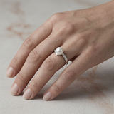 Anillo de oro blanco adornado con diamantes y perla blanca.