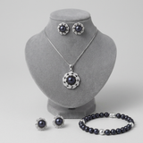 Parure collier, boucles d'oreilles et bracelet perles noires sur présentoir gris.