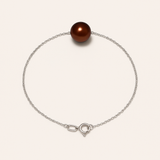 Le bracelet Perlinea Argent & Perle de Culture Chocolat - 8/9mm est composé d'une délicate chaîne en argent 925 avec une seule perle ronde d'eau douce chocolat, sécurisée par un fermoir lobster et un anneau de saut, présenté sur un fond blanc.
