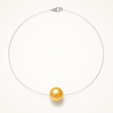Le Collier SOFIA | Perle Dorée de Perlinea se compose d'une chaîne délicate, presque invisible, et d'un pendentif en forme de perle de culture ronde, élégamment mis en valeur sur un fond blanc uni.