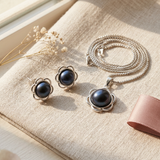 Collier et boucles d'oreilles à perles noires serties dans un motif floral argenté.