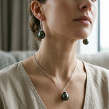 Collier et boucles d'oreilles pendantes avec perles de Tahiti noires portés sur cou et oreilles.