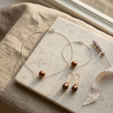Parure collier, bracelet et boucles d'oreilles avec perles chocolat sur chaîne argentée et dorée.