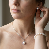 Parure collier, boucles et bracelet de perles blanches portée sur cou, oreille et poignet.