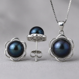 Parure collier et boucles d'oreilles serties d'une perle noire aux reflets bleutés, monture fleurie.